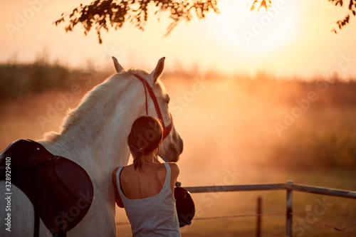Young rider girl with her horse at sunset.