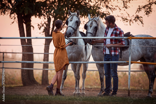 Smiling woman and men on the ranch at sunset with their horses for a ride