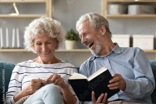 Bild auf Leinwand Overjoyed elderly mature couple spouses sit rest on couch in living room engaged