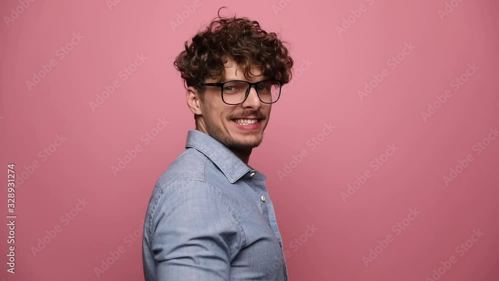 casual man wearing glasses posing in rear view then turning around into side view and smiling happy finally turning into front view on pink studio background casual man wearing glasses posing in rear view then turning around into side view and smiling happy finally turning into front view on pink studio background
