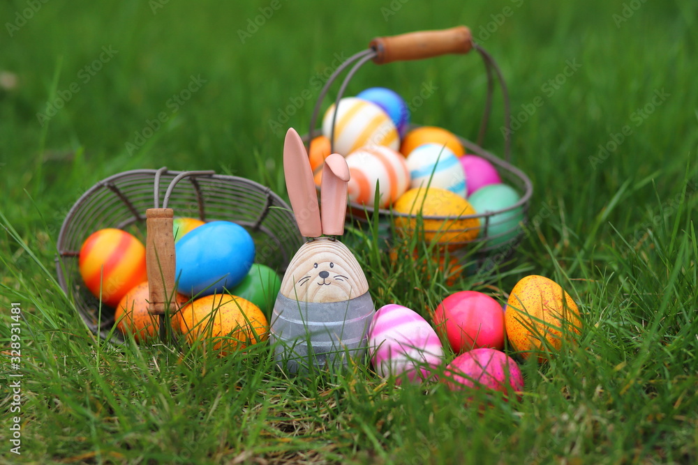 Fototapeta premium bunte eier im drahtkorb auf der wiese mit osterhasen