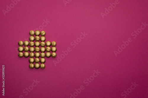 pills in cross shape on pink background