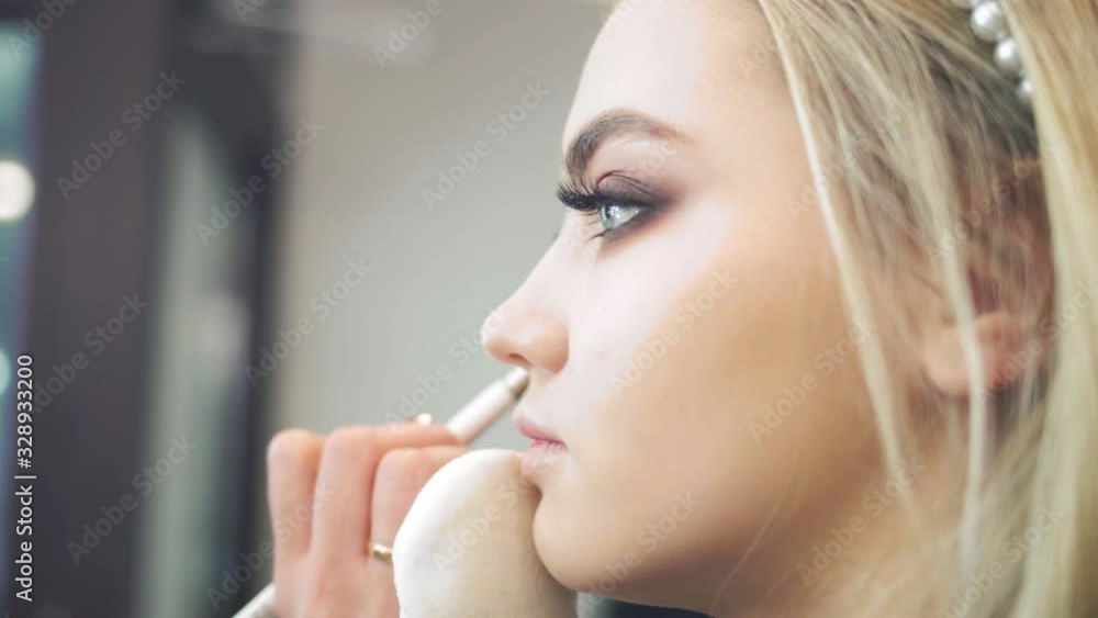 A woman paints her eyes with makeup brushes. A beautiful woman is being made up. Preparing the model for shooting. Professional makeup artist. Beauty salon. A woman paints her eyes with makeup brushes. A beautiful woman is being made up. Preparing the model for shooting. Professional makeup artist. Beauty salon.