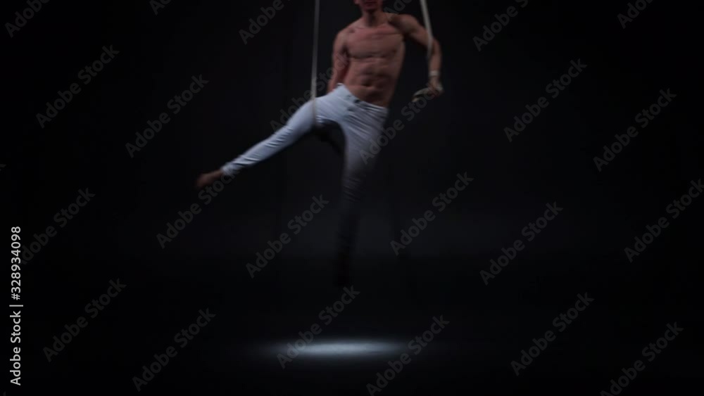 Muscular circus artist on the aerial straps. Concept of power, health and wellness Muscular circus artist on the aerial straps. Concept of power, health and wellness