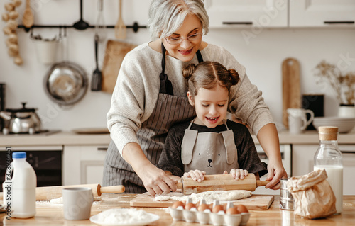 happy family grandmother and granddaughter child cook in the kitchen, knead dough, bake cookies.