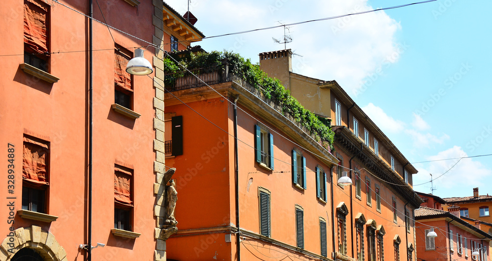 Red terracotta facades of buildings and window shutters at street in Bologna, Italy