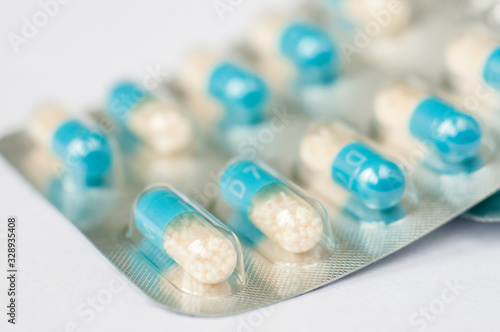 Closeup blue-white antibiotics capsule pills in blister pack. Pharmacy background. Antimicrobial drug resistance. Pharmaceutical industry. Global healthcare.