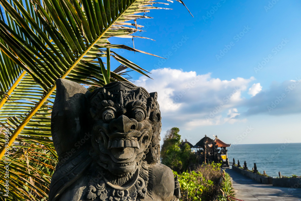 A guardian God at the promenade to a small temple in Tanah Lot temple complex on Bali, Indonesia, located at the seashore. The figure of the God looks aggressive. Historical and traditional Hindu site A guardian God at the promenade to a small temple in Tanah Lot temple complex on Bali, Indonesia, located at the seashore. The figure of the God looks aggressive. Historical and traditional Hindu site