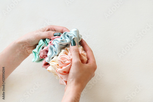 Lot of Colorful silk Scrunchies on womas hand on white background. Hairdressing tools and accessories. Hair Scrunchies, Elastic HairBands, Bobble Sports Scrunchie Hairband for girls. copy space