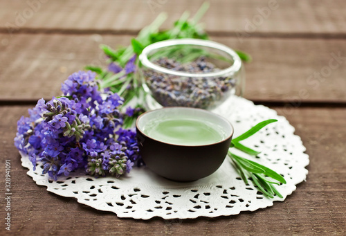 Lavender tea in clay cup with fresh and dry lavender flowers on a wooden background.