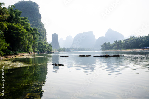 A view along the banks of the Li River, Yangshuo, Guilin, China. With bamboo forests on either side and distant mountains fading into the mist.