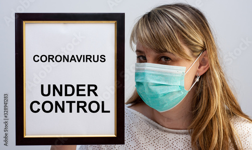 Beautiful european woman holding a frame with a Coronavirus related text Under Control