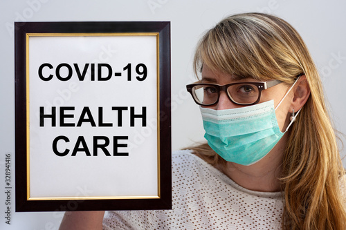 Beautiful european woman holding a frame with a COVID-19 related text Health Care