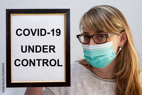 Beautiful european woman holding a frame with a COVID-19 related text Under Control