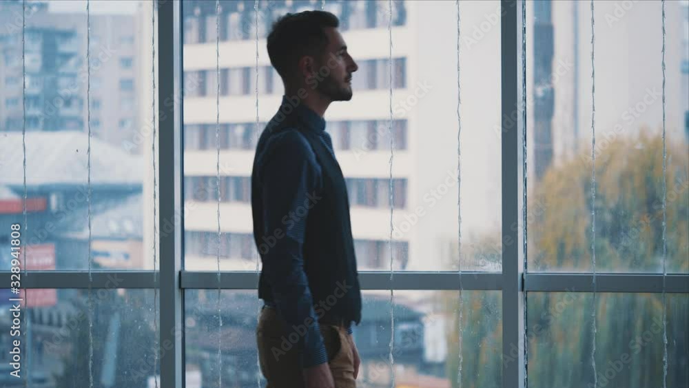 Businessman in formal suite stands in front of panoramic window with city view. Close up. Slow motion. Slowmo. 4K. Businessman in formal suite stands in front of panoramic window with city view. Close up. Slow motion. Slowmo. 4K.