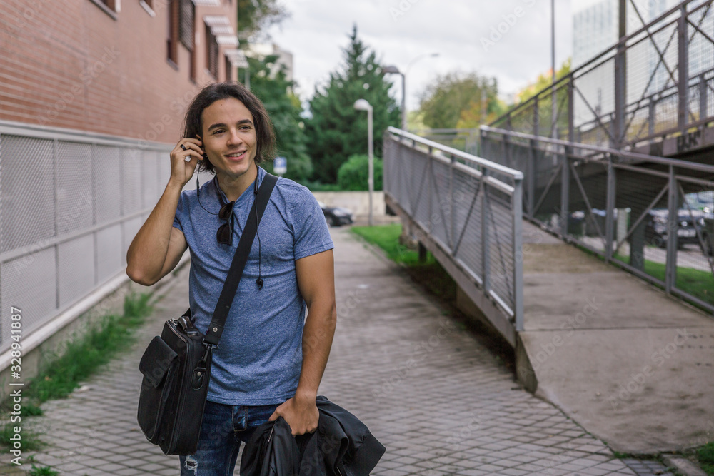 Obraz premium Handsome young man with casual style smiles while listening to music with his headphones