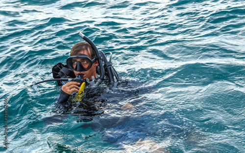 young diver in a suit and mask for diving shows signal that everything is fine after jumping into the water.
