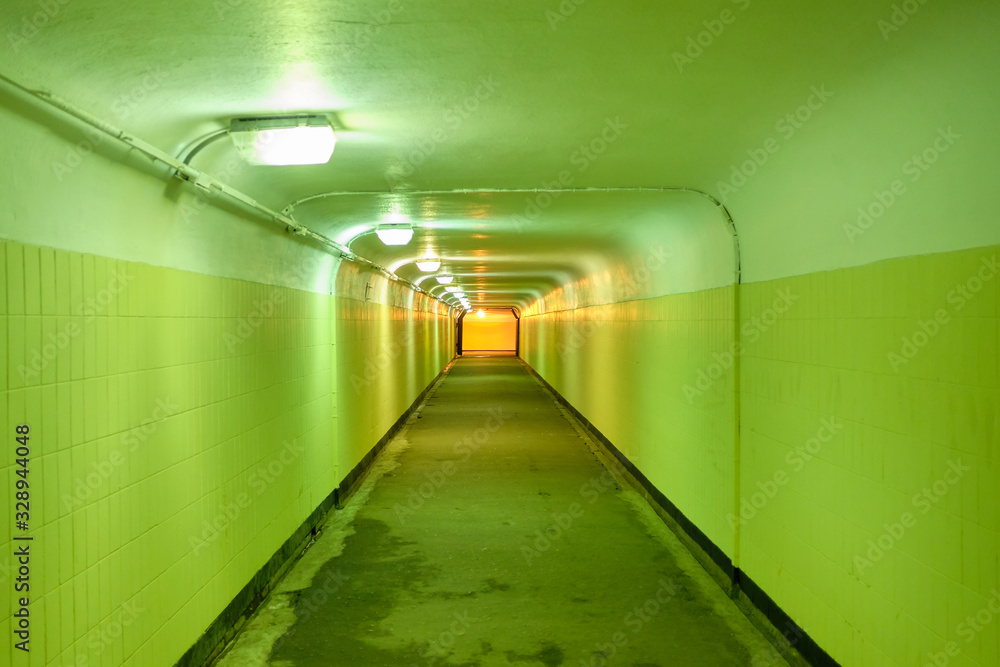 Underground pedestrian tunnel with green walls.