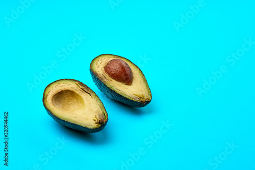 Two slices of avocado isolated on the blue background. One slice with core.