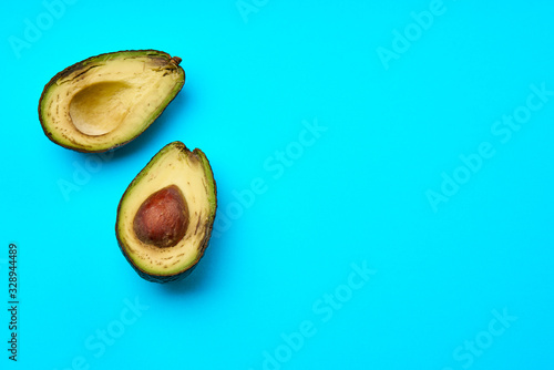 A rotten avocado cut in half on blue background.