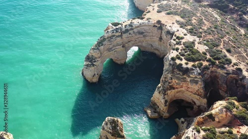 Ocean eroded rock arch formations in Marinha Beach south of Portugal, Aerial approach shot photo