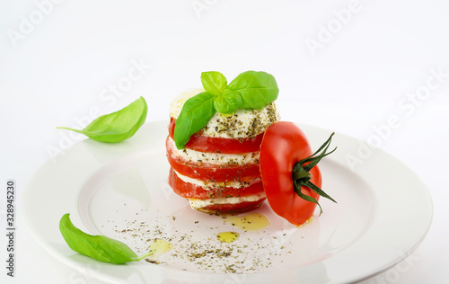 Concetto di cucina italiana. Insalata caprese con fette di pomodoro, mozzarella, basilico, olio d'oliva. Sfondo bianco