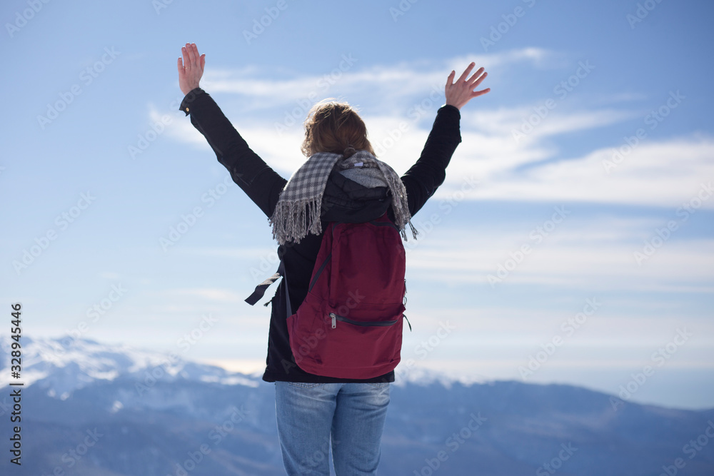 The girl on the snowy peak raised her hands up. A traveler at a mountain ski resort stands on the edge. A man on top. Winter weather. The girl on the snowy peak raised her hands up. A traveler at a mountain ski resort stands on the edge. A man on top. Winter weather.