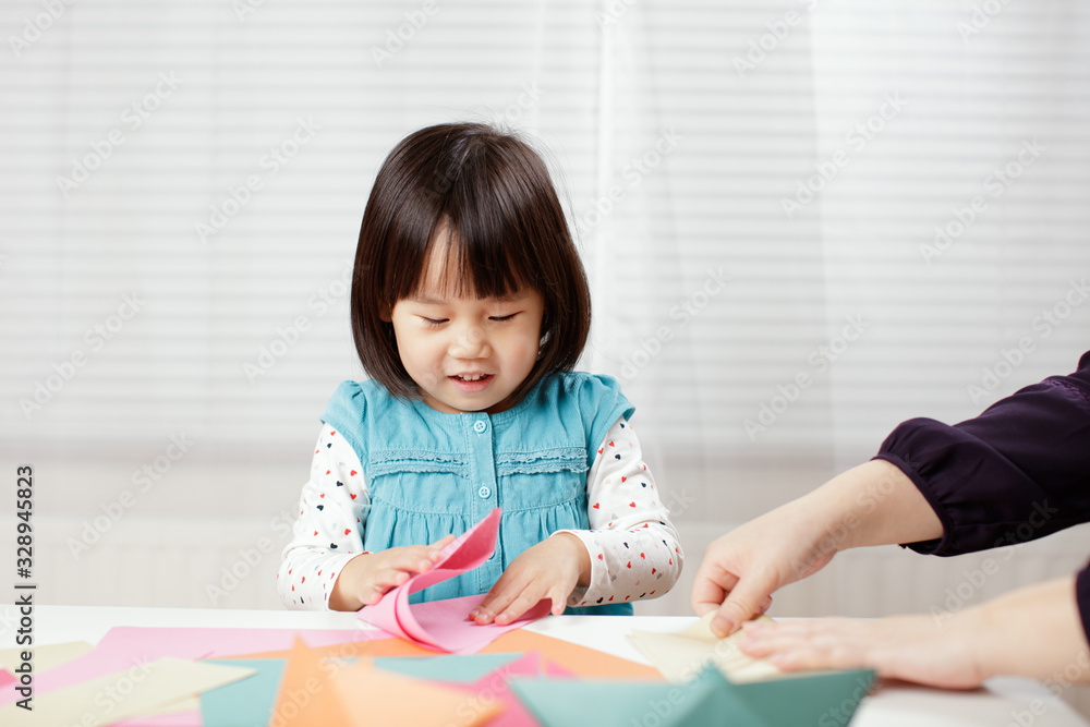 toddler girl learn making Origami at home against white background toddler girl learn making Origami at home against white background