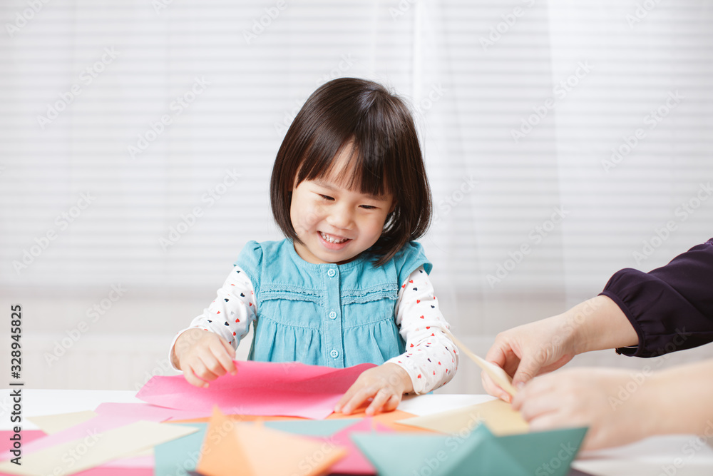 toddler girl learn making Origami at home against white background toddler girl learn making Origami at home against white background