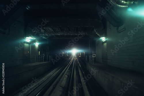 Dubai metro tunnel in blurred motion with light in end, view from first wagon, subway tracks.
