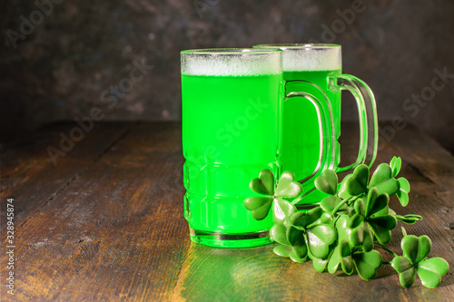 Mugs of green beer and a branch of shamrock on the wooden table for celebrating Saint Patrick's Day, national irish holiday.