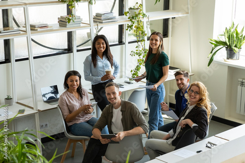 Portrait of smiling diverse businesspeople gather in modern office brainstorm business ideas together, happy multiracial colleagues coworkers cooperate at briefing, engaged in teambuilding activity