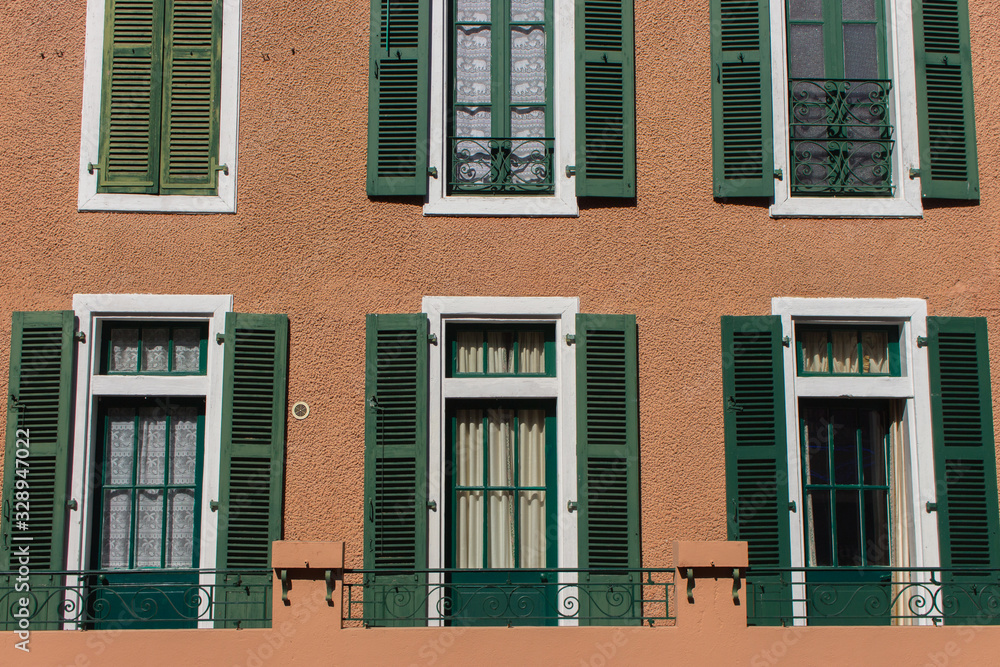 Windows with green wooden shutters. Facade of old building. Traditional ancient architecture in Europe. Vintage exterior of house. 