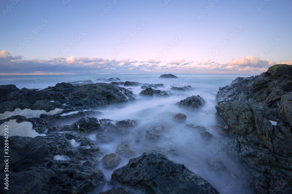 gorgeous sunset long exposure on the beach with sea waves and cliffs