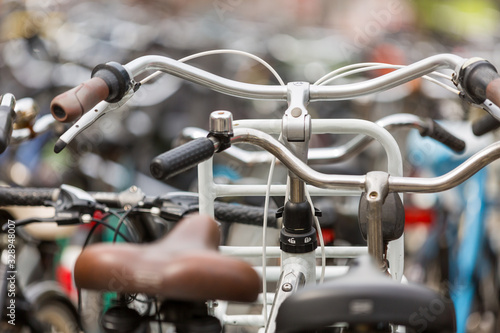 Close up of the handlebars of a group of parked dutch bicycles against a bokeh background