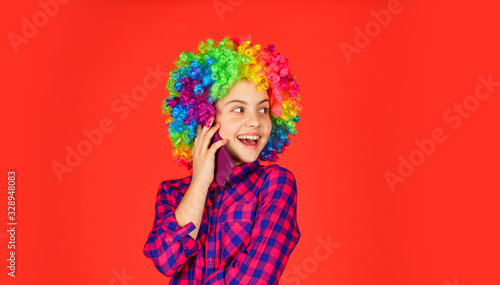 positive and cheerful. childhood happiness. kid looking funny in rainbow wig hair. hair dyeing at hairdresser. child having fun. happy birthday party. small girl colorful wig speak on phone.