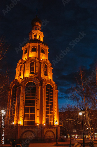 Side view of bell tower highlighted by flashlights. Venus shining in the dawn sky