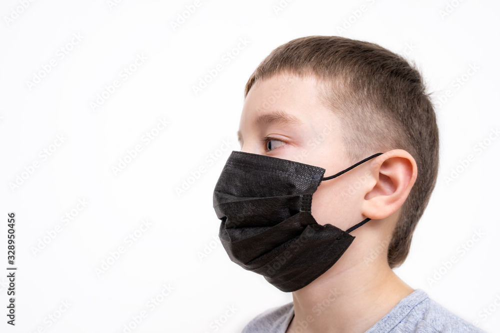 A portrait of a boy wearing surgical medical black face mask on white background A portrait of a boy wearing surgical medical black face mask on white background