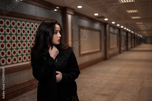 a young beautiful woman walks through an underground passage at night, looking back with fear.mosaics on the walls are not paintings, not someone's works of art. it's just walls in eastern style.  