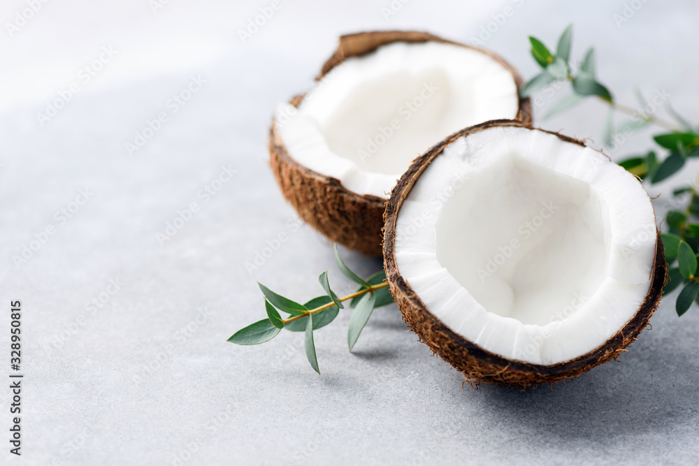 Halved coconut on concrete background with copy space for text or design elements Halved coconut on concrete background with copy space for text or design elements