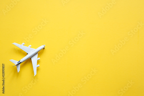 Toy plane on a pastel yellow background with top view and copy space. Travel concept.