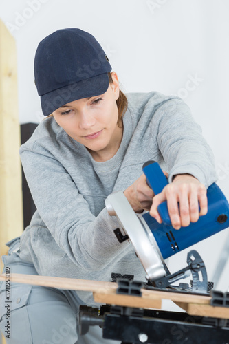 beautiful female carpenter using a circular saw