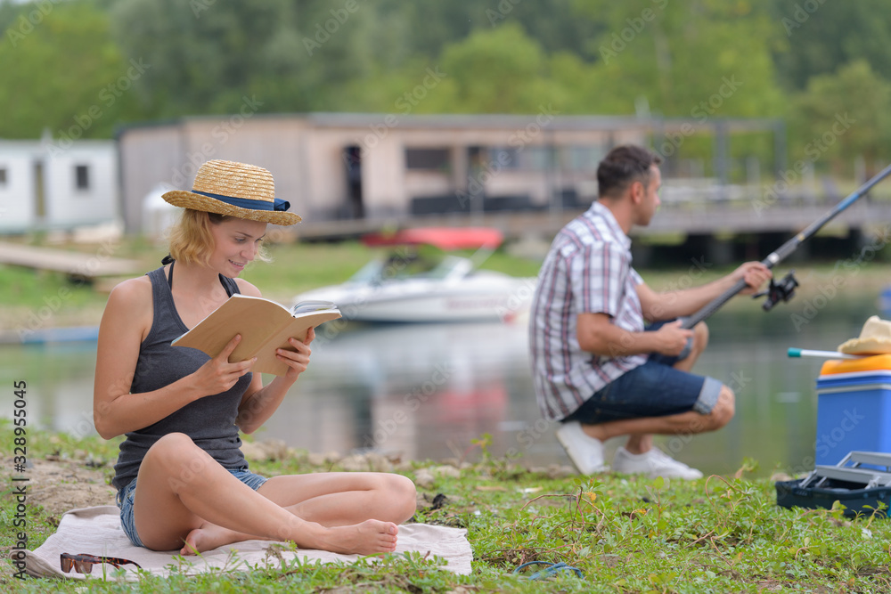 couple relaxing in nature fishing and reading