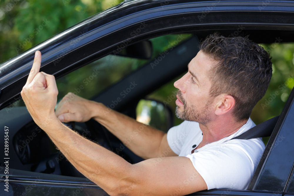 man driving a car and showing the middle finger