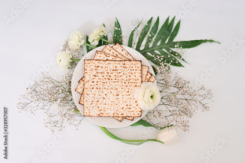 Passover background with matzoh and spring flower ranunculus. Top view with copy space. Happy Passover Spring Festive season greeting card. Jewish holidays arrangement photo