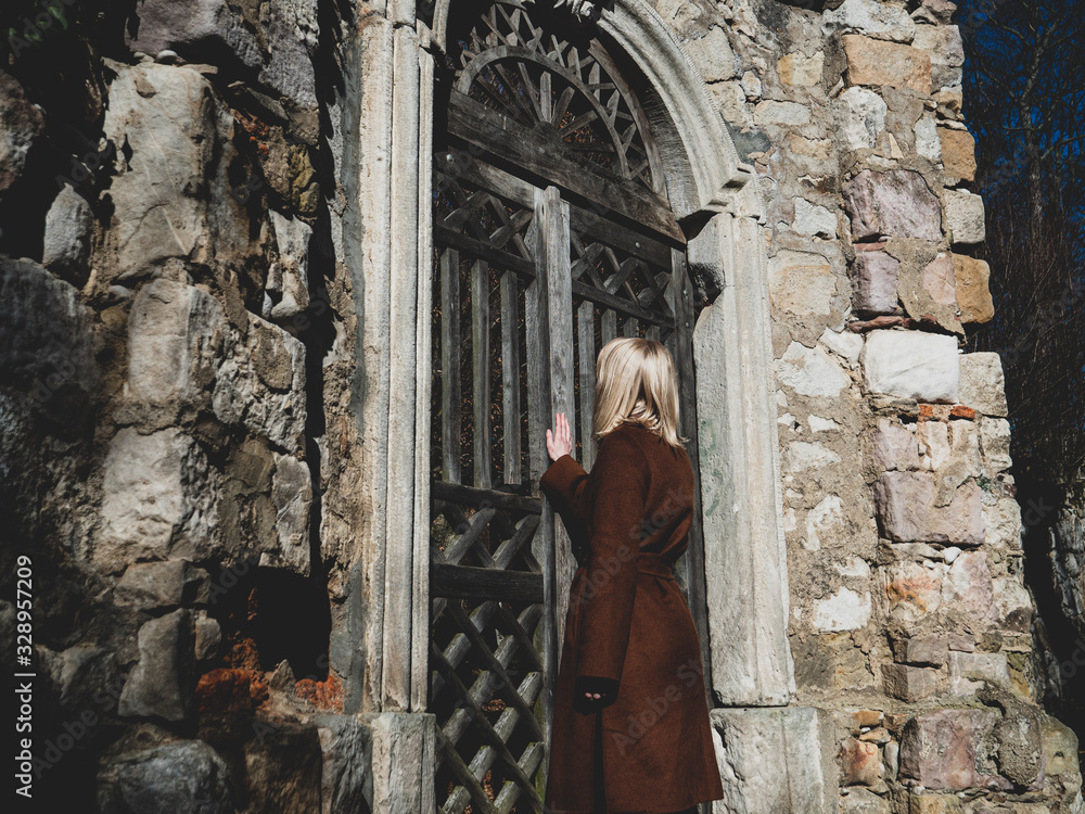 Blonde woman near ruins of old door in a castle