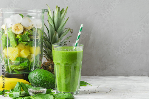 Blender with fresh ingredients to making healthy detox smoothie with glass of green prepared drink with a straw photo