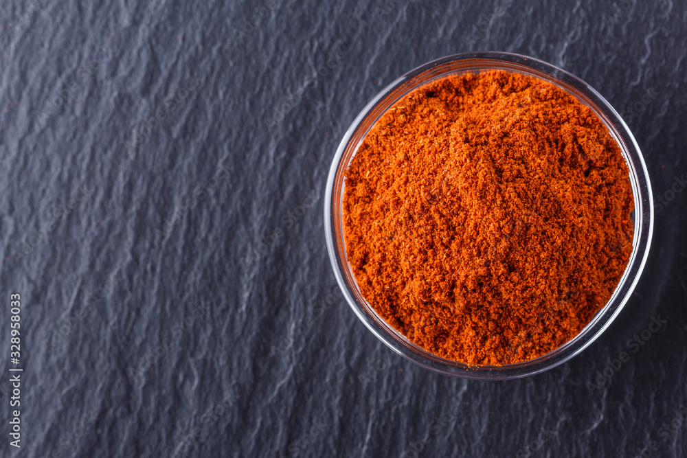 aromatic spicy chilli powder on a dark stone background aromatic spicy chilli powder on a dark stone background