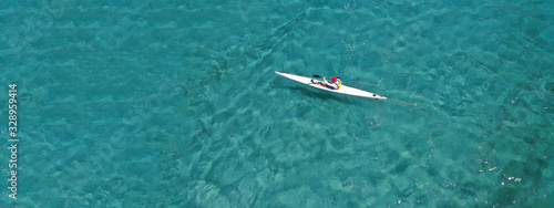 Aerial drone ultra wide photo of fit men competing in sport canoe in tropical exotic bay with emerald sea
