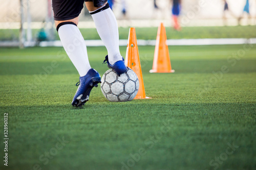 Soccer player jogging and control ball around cone markers for soccer training.